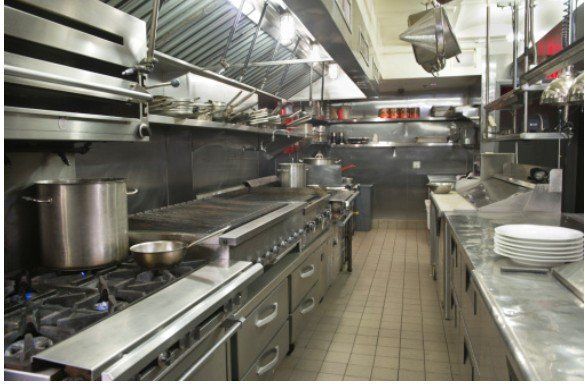 Commercial kitchen line with gas burners and stainless steel surfaces
